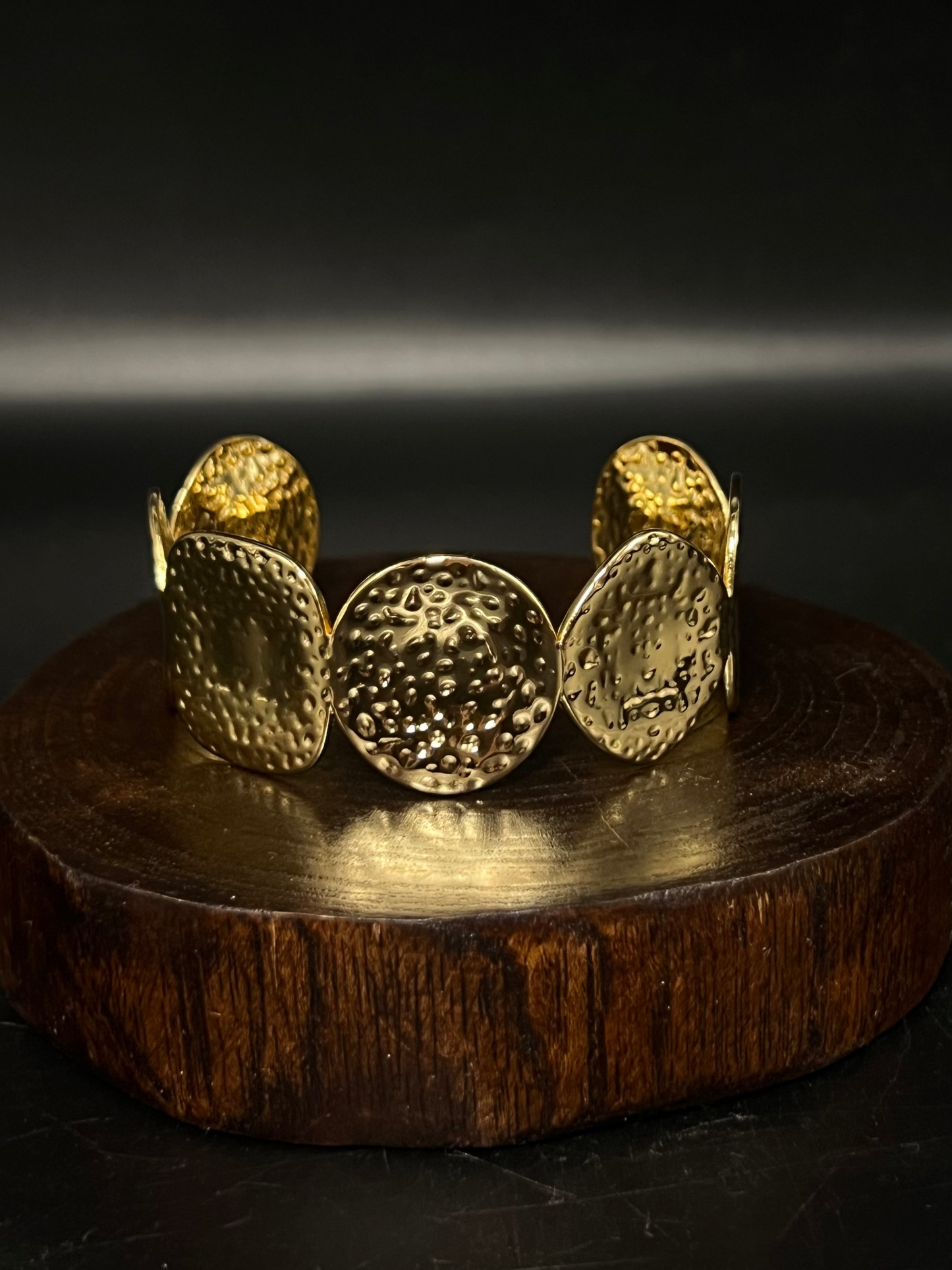 Gold bracelet on a wooden stand with a dark background